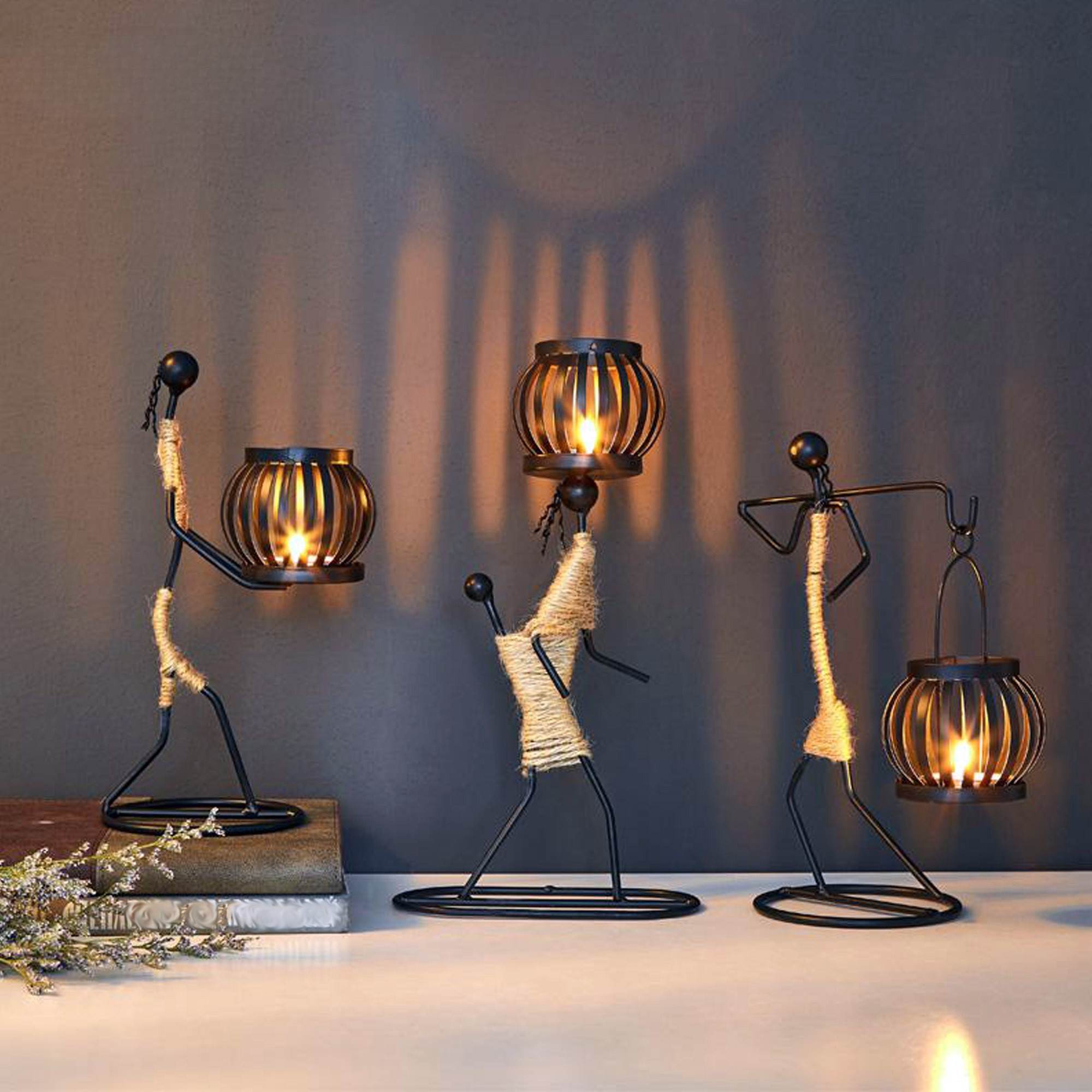 Handcrafted tribal lady metal candle holder with jute wrapping and matte black finish, holding a flickering tea light candle on a rustic wooden table
