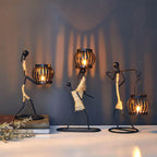 Handcrafted tribal lady metal candle holder with jute wrapping and matte black finish, holding a flickering tea light candle on a rustic wooden table