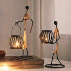 Handcrafted tribal lady metal candle holder with jute wrapping and matte black finish, holding a flickering tea light candle on a rustic wooden table