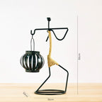 Handcrafted tribal lady metal candle holder with jute wrapping and matte black finish, holding a flickering tea light candle on a rustic wooden table