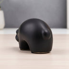Minimalist matte black ceramic bear sculpture set on wooden surface 