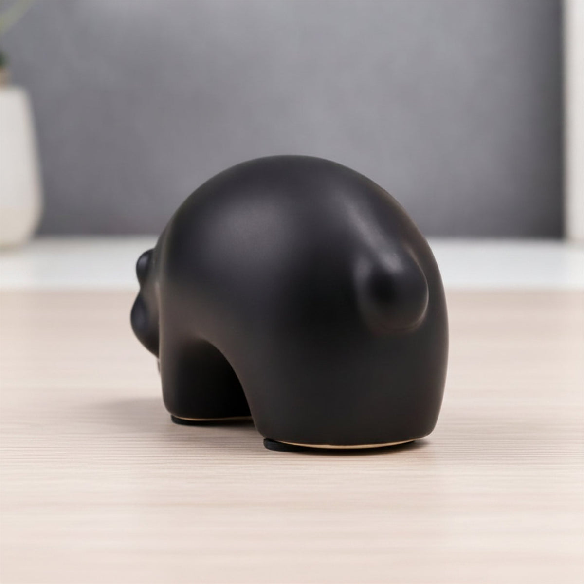 Minimalist matte black ceramic bear sculpture set on wooden surface 