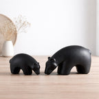 Minimalist matte black ceramic bear sculpture set on wooden surface with modern lifestyle background
