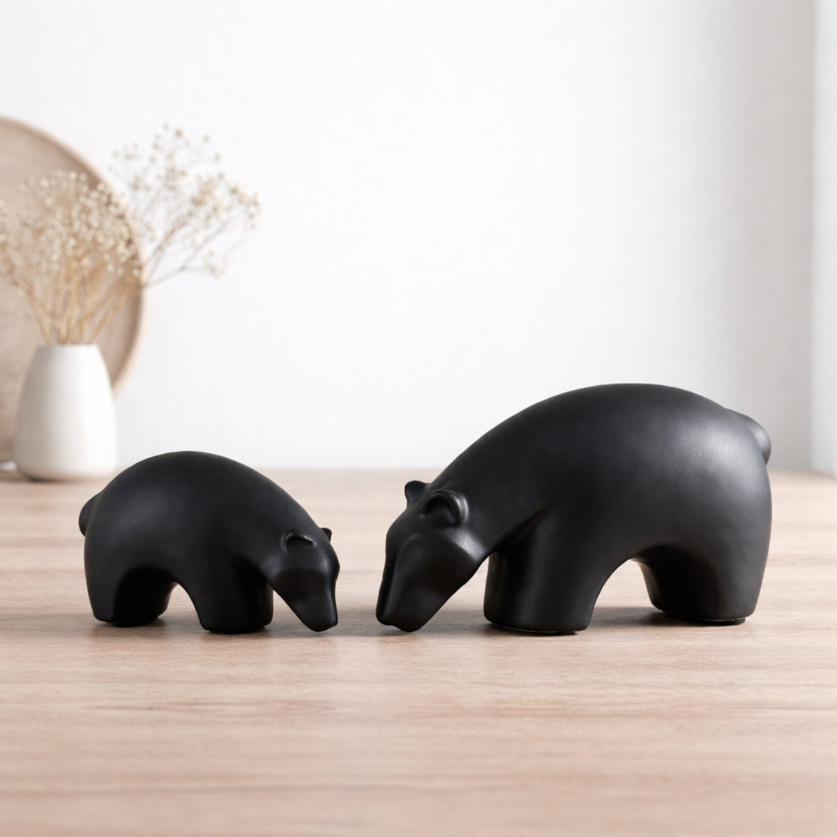 Minimalist matte black ceramic bear sculpture set on wooden surface with modern lifestyle background