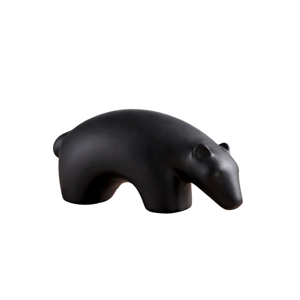 Minimalist matte black ceramic bear sculpture set on wooden surface 