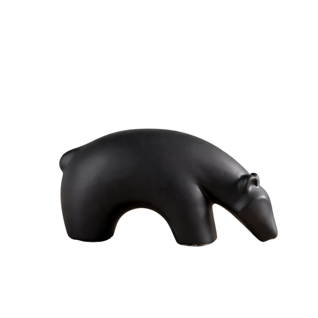 Minimalist matte black ceramic bear sculpture set on wooden surface 