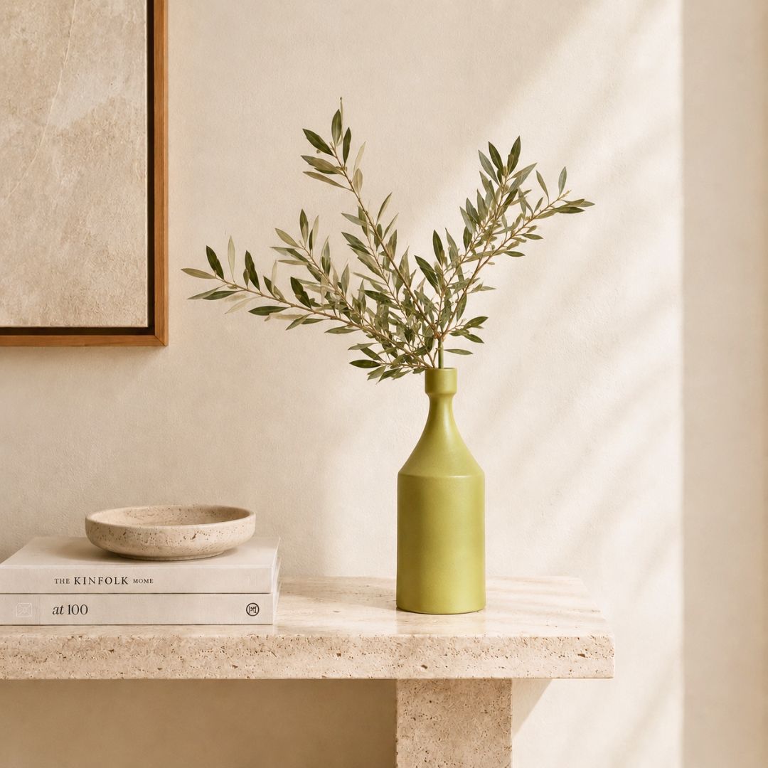 Luxury ceramic bottle-shaped vase with matte finish styled on a beige travertine console table in a modern Scandinavian-inspired interior with olive branches and minimalist décor.