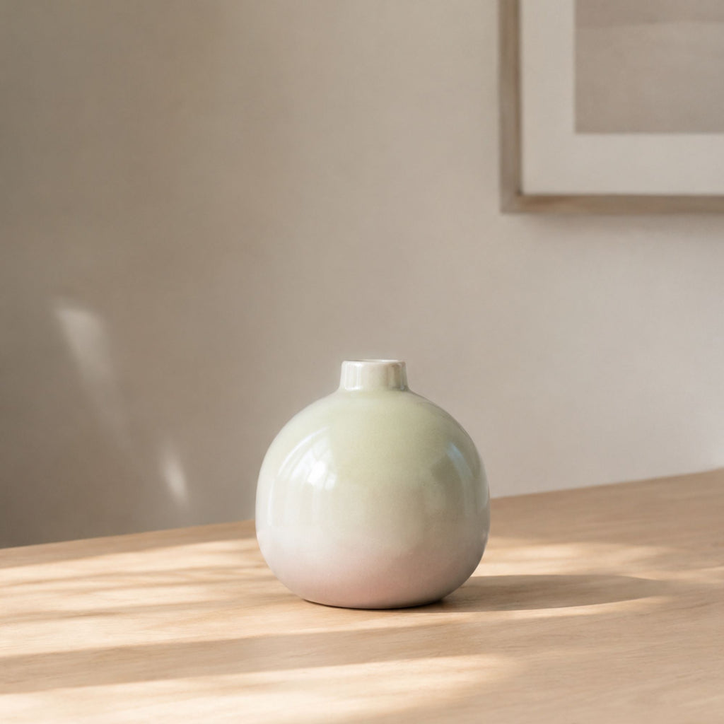 Luxury round ceramic flower vase in minimalist modern design held in hand against vibrant pink background for premium home décor and office styling.