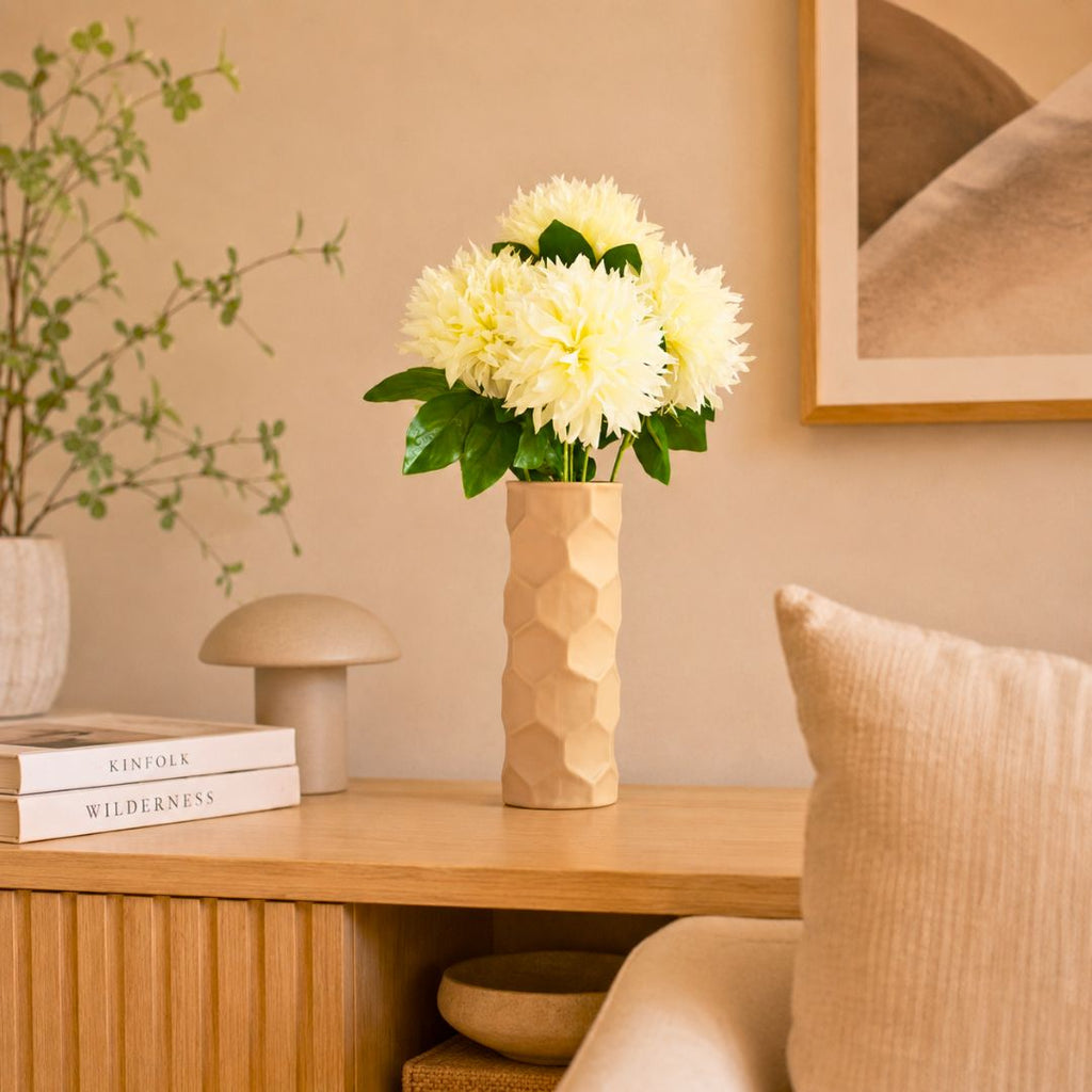Luxury beige honeycomb ceramic flower vase with white flowers styled on a wooden console table in a modern minimalist living room interior.