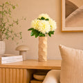 Luxury beige honeycomb ceramic flower vase with white flowers styled on a wooden console table in a modern minimalist living room interior.