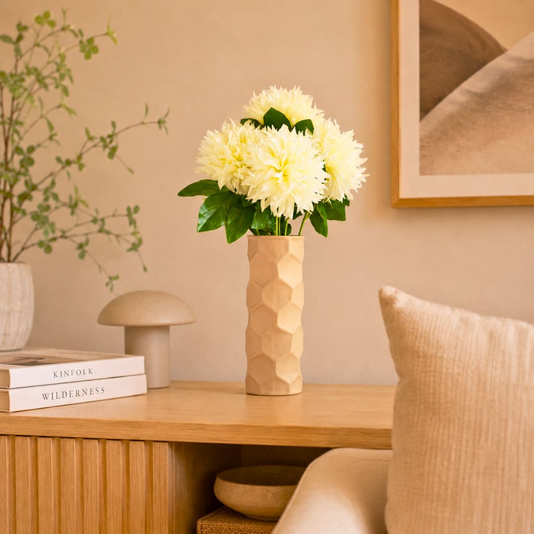 Luxury beige honeycomb ceramic flower vase with white flowers styled on a wooden console table in a modern minimalist living room interior.