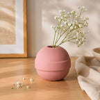 Pink vase with white flowers on a wooden surface
