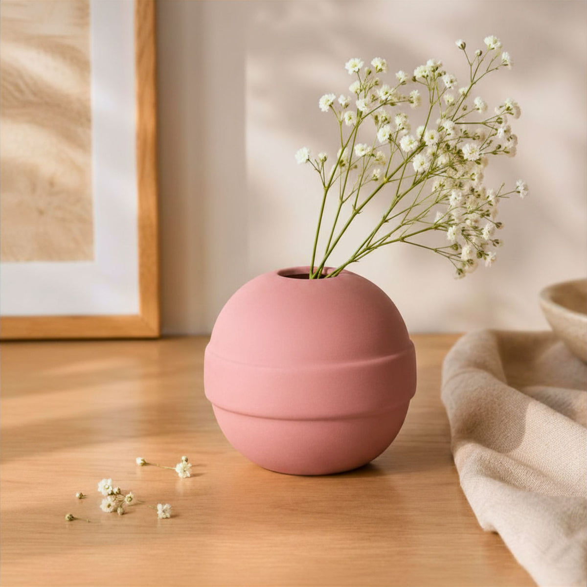 Pink vase with white flowers on a wooden surface