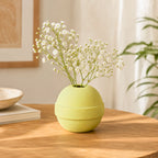Green vase with white flowers on a wooden table