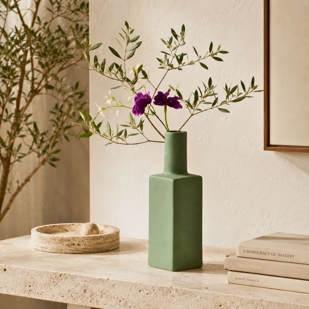 Luxury ceramic bottle-shaped vase with matte finish styled on a beige travertine console table in a modern Scandinavian-inspired interior with olive branches and minimalist décor.