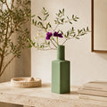 Luxury ceramic bottle-shaped vase with matte finish styled on a beige travertine console table in a modern Scandinavian-inspired interior with olive branches and minimalist décor.