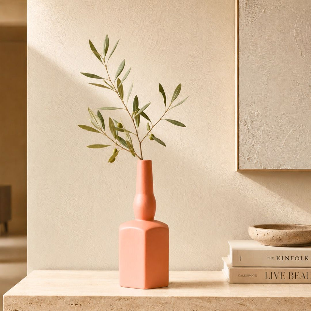 Luxury ceramic bottle-shaped vase with matte finish styled on a beige travertine console table in a modern Scandinavian-inspired interior with olive branches and minimalist décor.