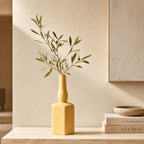 Luxury ceramic bottle-shaped vase with matte finish styled on a beige travertine console table in a modern Scandinavian-inspired interior with olive branches and minimalist décor.