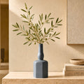 Luxury ceramic bottle-shaped vase with matte finish styled on a beige travertine console table in a modern Scandinavian-inspired interior with olive branches and minimalist décor.