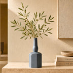 Luxury ceramic bottle-shaped vase with matte finish styled on a beige travertine console table in a modern Scandinavian-inspired interior with olive branches and minimalist décor.