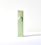 Modern sculptural ceramic flower vase with matte sage green finish styled with tropical leaf in a contemporary luxury interior setting.