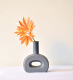 Modern hollow flat ceramic vase with sculptural circular design styled on a console table in a contemporary luxury living room interior.