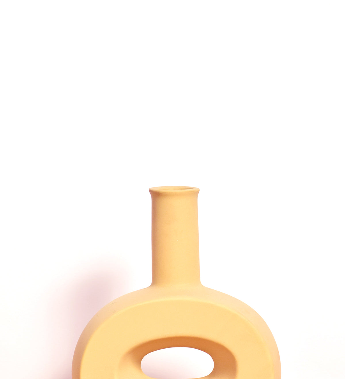 Modern hollow flat ceramic vase with sculptural circular design styled on a console table in a contemporary luxury living room interior.