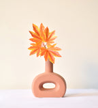 Modern hollow flat ceramic vase with sculptural circular design styled on a console table in a contemporary luxury living room interior.
