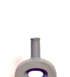 Modern hollow flat ceramic vase with sculptural circular design styled on a console table in a contemporary luxury living room interior.