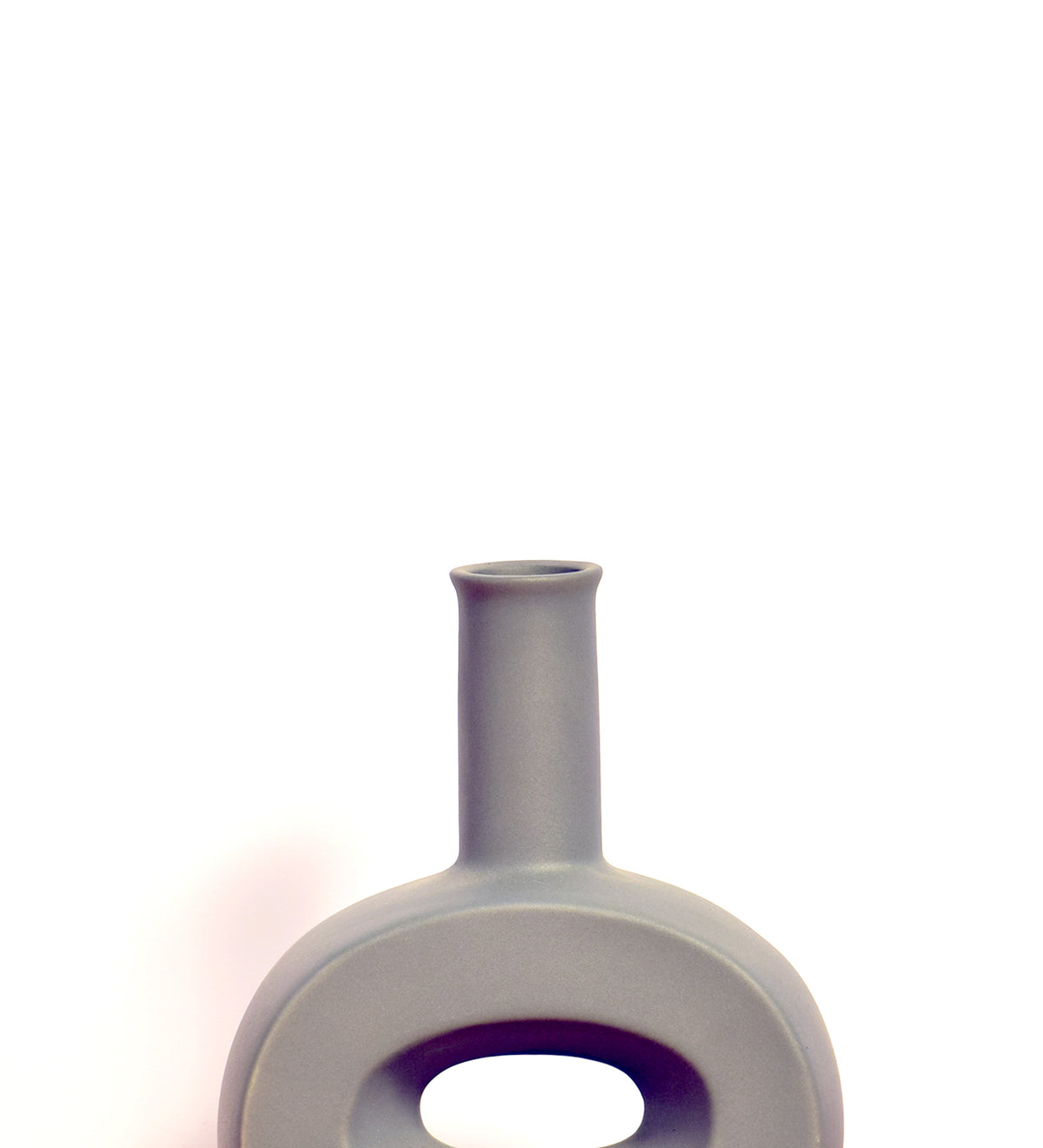 Modern hollow flat ceramic vase with sculptural circular design styled on a console table in a contemporary luxury living room interior.