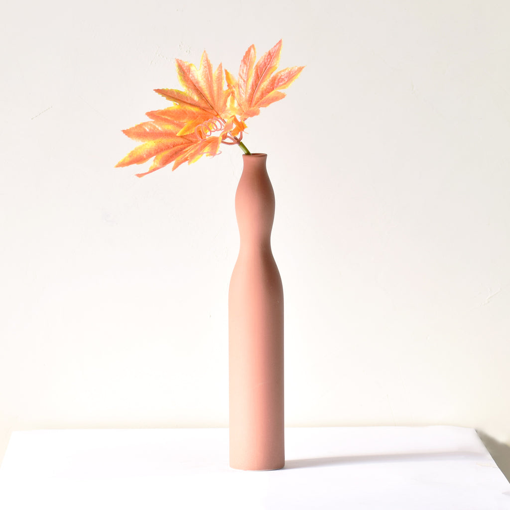 Luxury slim Nordic ceramic flower vase with matte grey finish and orange artificial maple leaves on white table for modern home décor interiors.