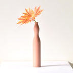 Luxury slim Nordic ceramic flower vase with matte grey finish and orange artificial maple leaves on white table for modern home décor interiors.