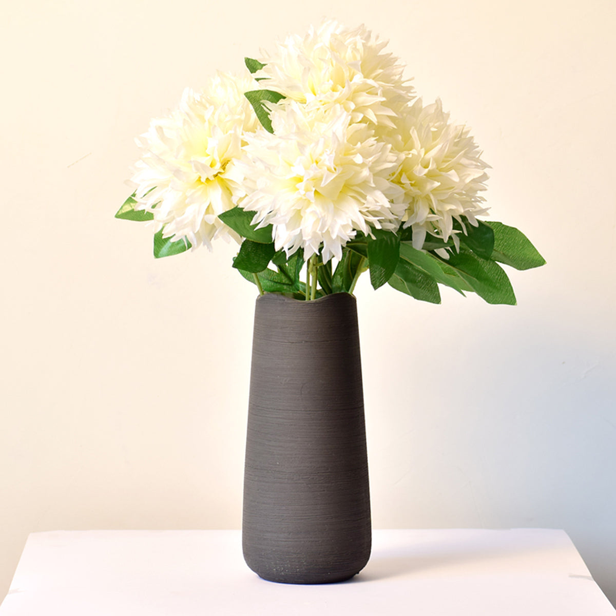 Elegant black ceramic flower vase with white floral arrangement on minimal background