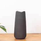 Elegant black ceramic flower vase with white floral arrangement on minimal background
