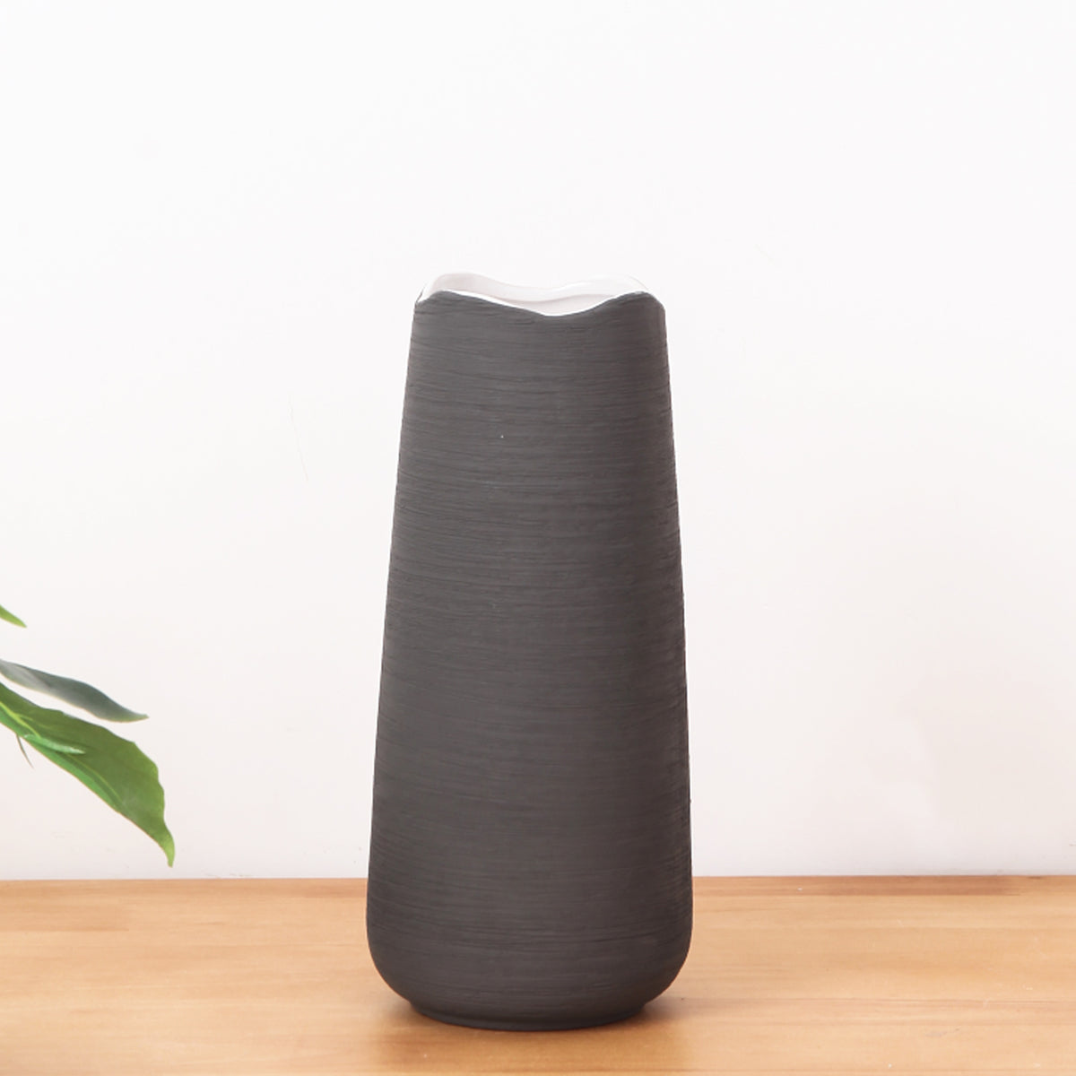 Elegant black ceramic flower vase with white floral arrangement on minimal background