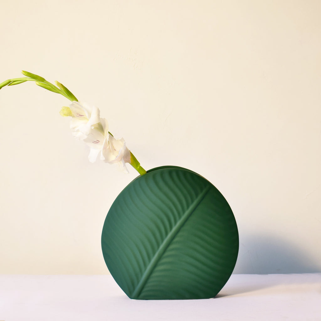 Elegant leaf-shaped ceramic decorative flower vase set with matte finish styled in a modern luxury Indian living room interior with fresh floral arrangement