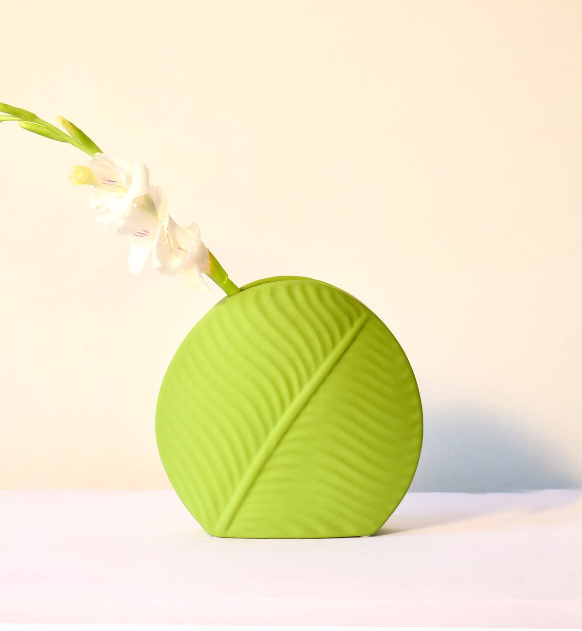 Mint green leaf ceramic flower vase styled with fresh blooms in a modern luxury living room featuring elegant contemporary décor.