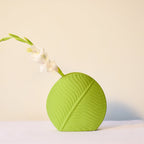 Mint green leaf ceramic flower vase styled with fresh blooms in a modern luxury living room featuring elegant contemporary décor.