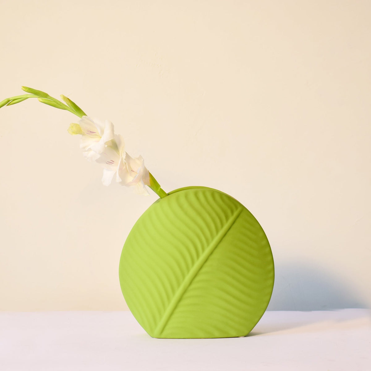 Mint green leaf ceramic flower vase styled with fresh blooms in a modern luxury living room featuring elegant contemporary décor.