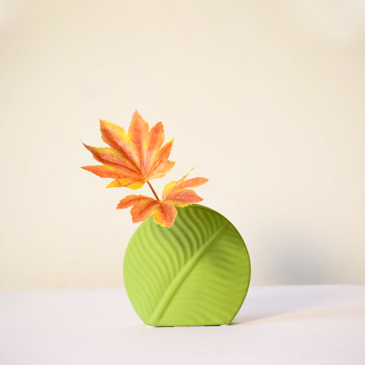 Mint green leaf ceramic flower vase styled with fresh blooms in a modern luxury living room featuring elegant contemporary décor.