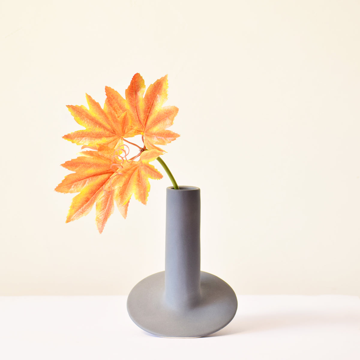 Handmade orbital ceramic flower vase with sculptural modern design styled with flowers in a luxury contemporary living room.