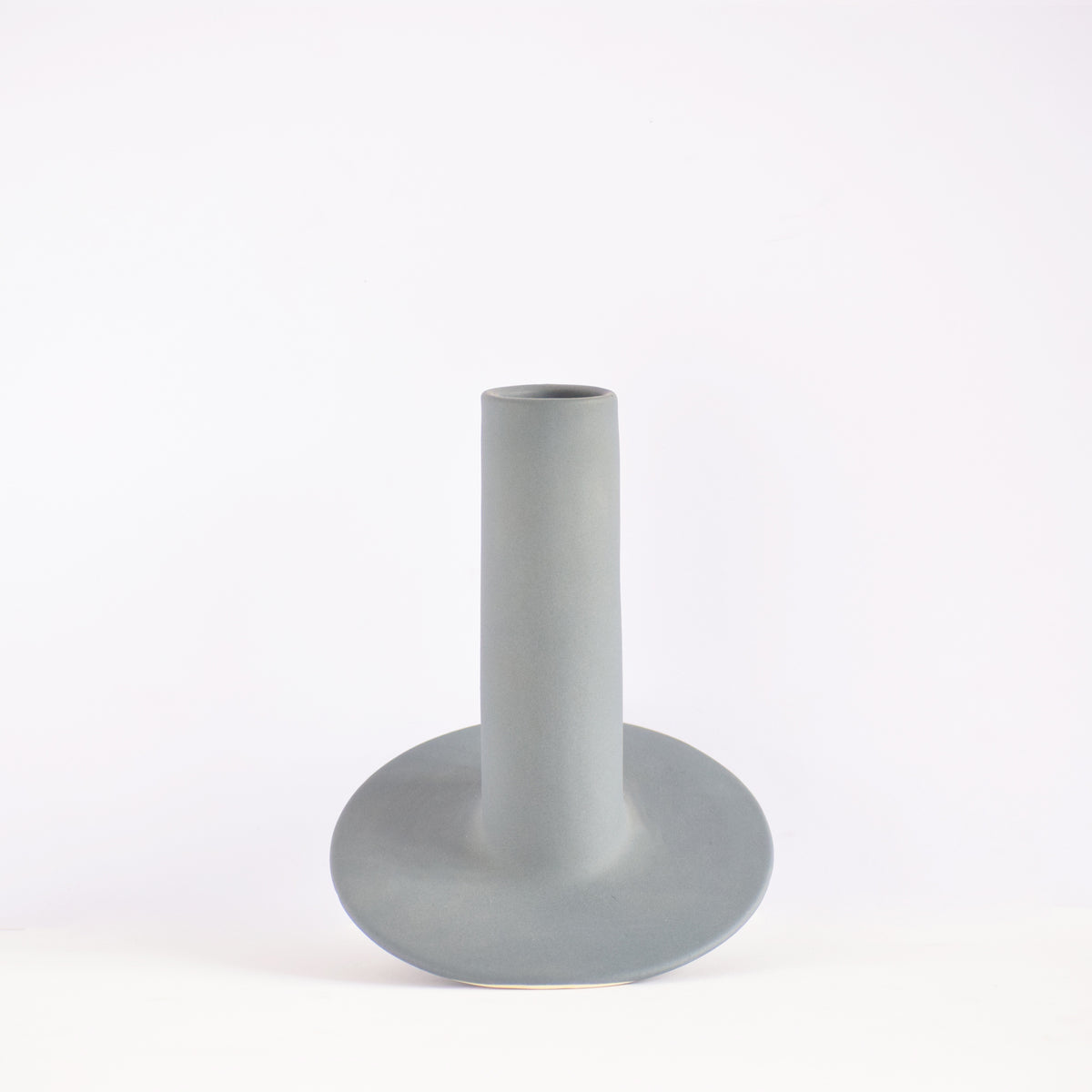 Handmade orbital ceramic flower vase with sculptural modern design styled with flowers in a luxury contemporary living room.