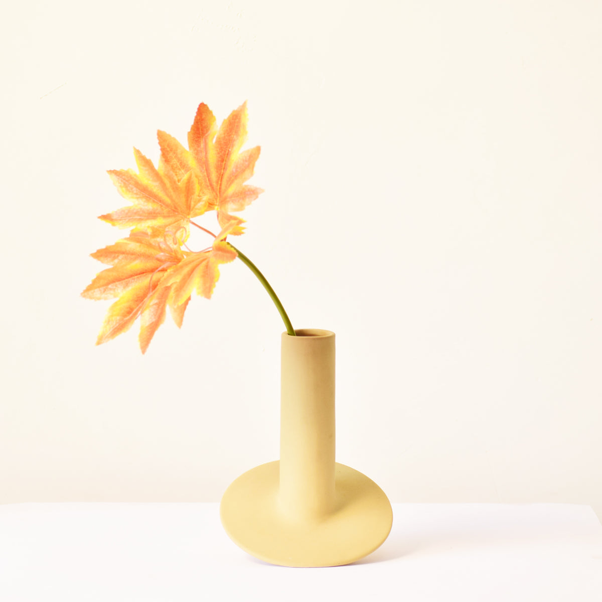 Handmade orbital ceramic flower vase with sculptural modern design styled with flowers in a luxury contemporary living room.