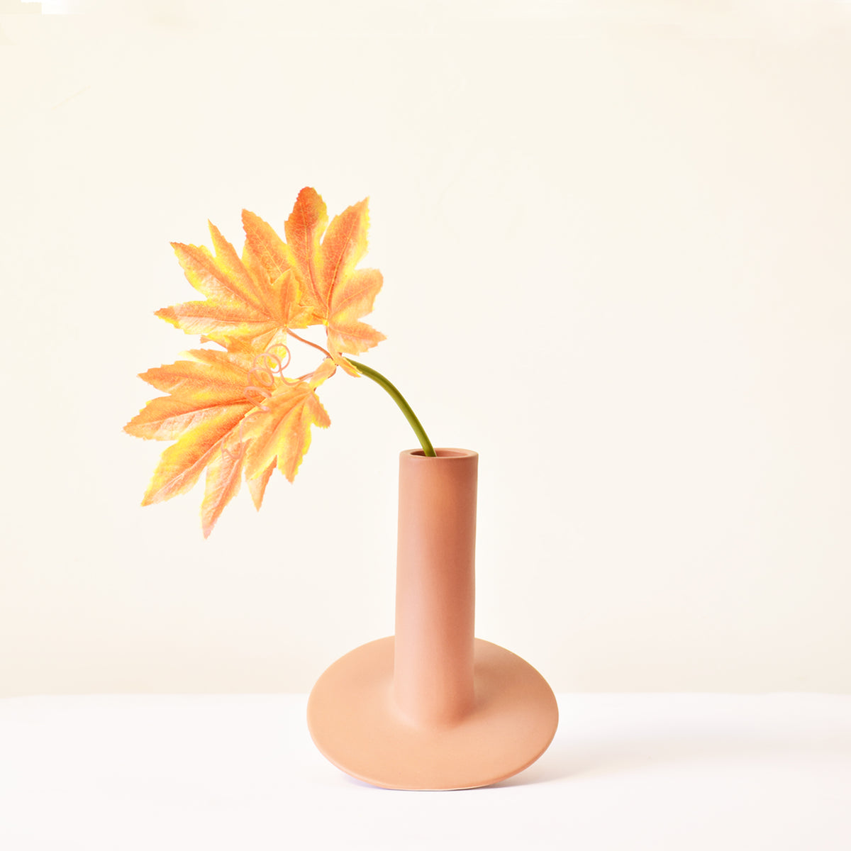 Handmade orbital ceramic flower vase with sculptural modern design styled with flowers in a luxury contemporary living room.