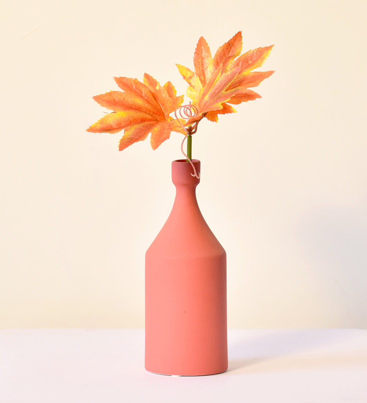 Luxury ceramic bottle-shaped vase with matte finish styled on a beige travertine console table in a modern Scandinavian-inspired interior with olive branches and minimalist décor.