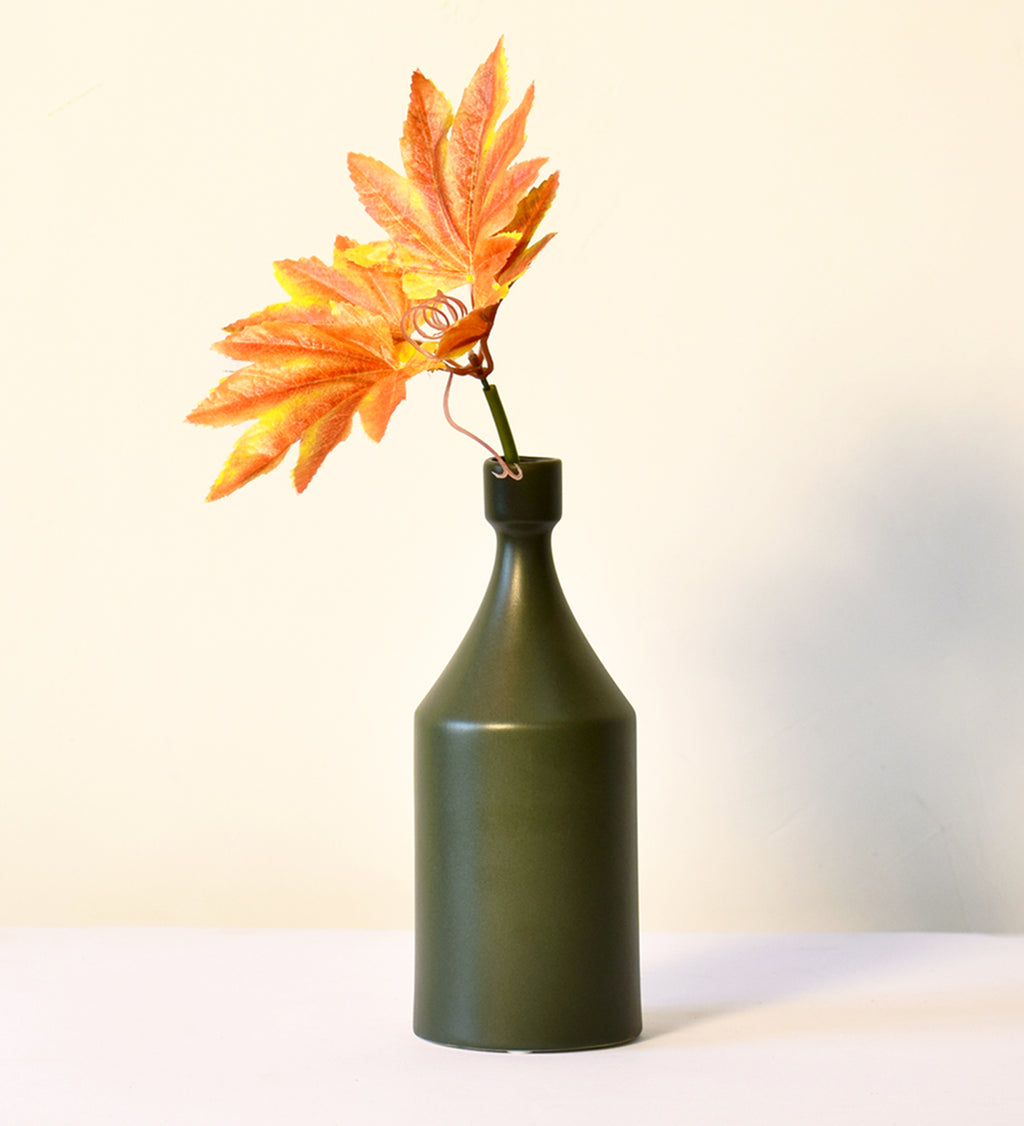 Luxury ceramic bottle-shaped vase with matte finish styled on a beige travertine console table in a modern Scandinavian-inspired interior with olive branches and minimalist décor.