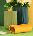 Modern dark green ribbed  u shaped ceramic flower vase with yellow floral arrangement on minimal beige background