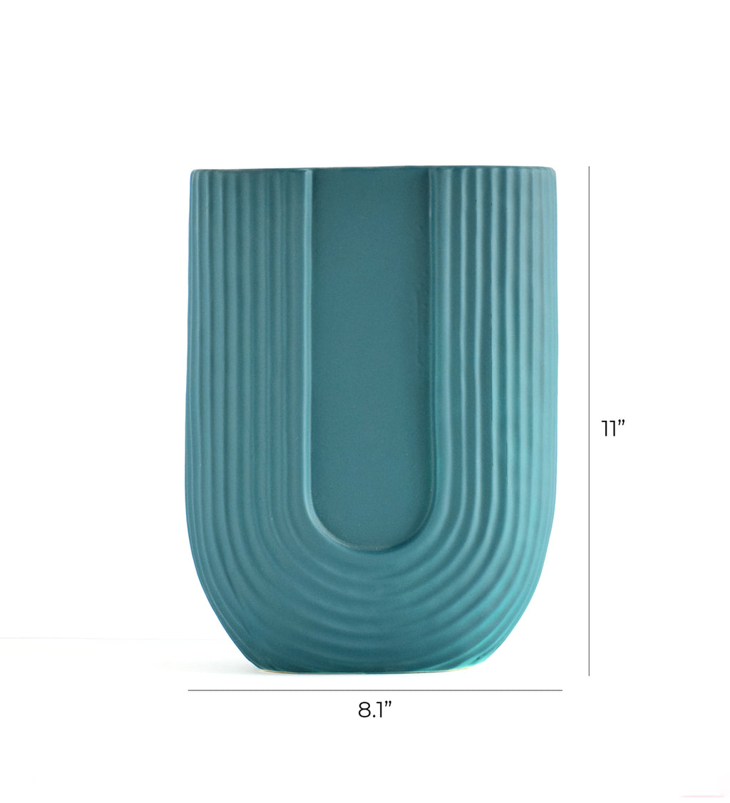Modern dark green ribbed ceramic flower vase with yellow floral arrangement on minimal beige background