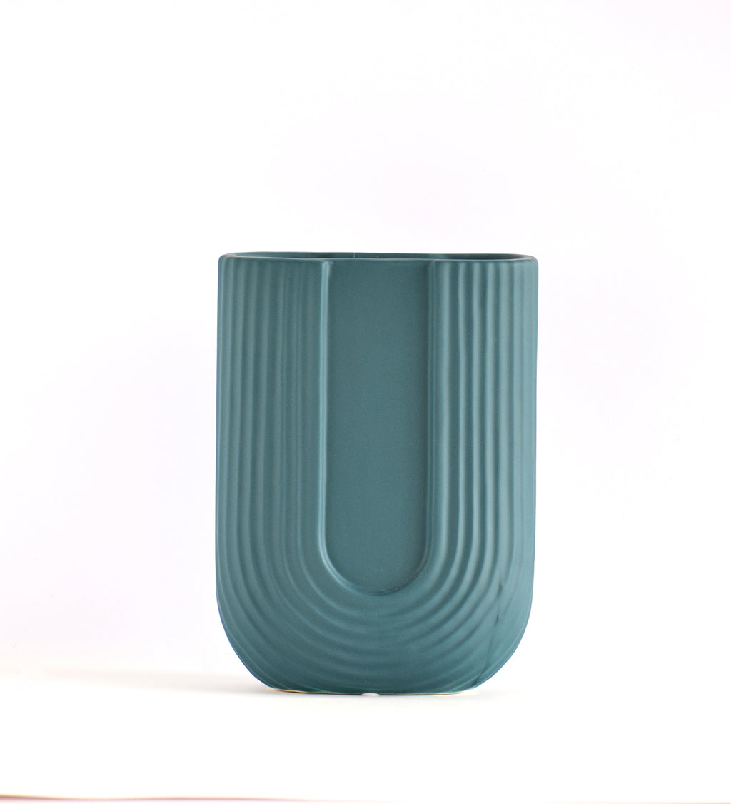 Modern dark green ribbed  u shaped ceramic flower vase with yellow floral arrangement on minimal beige background