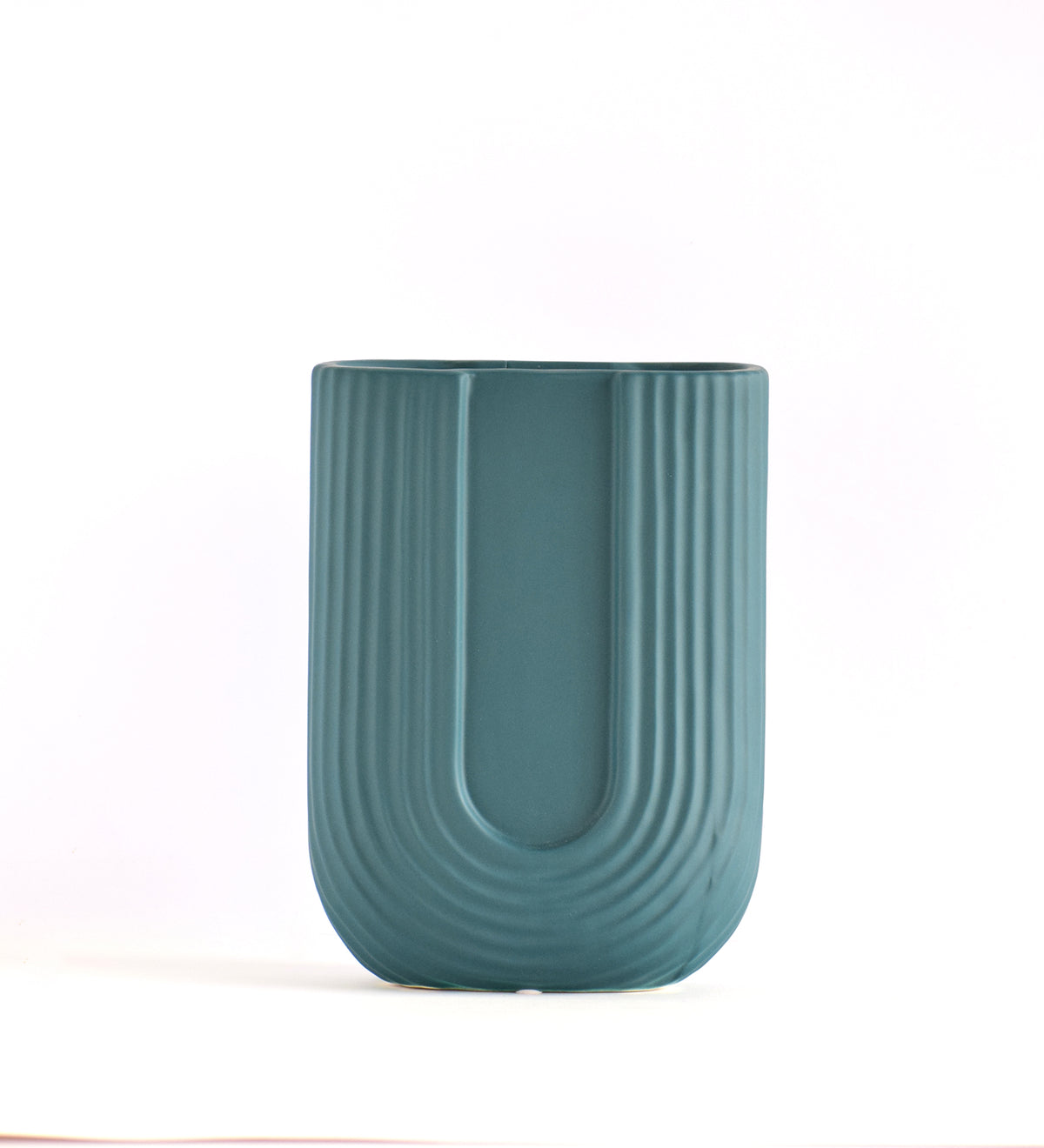 Modern dark green ribbed  u shaped ceramic flower vase with yellow floral arrangement on minimal beige background